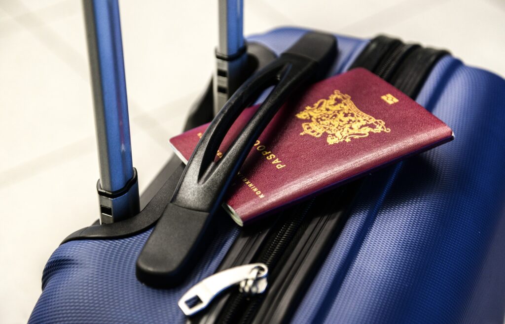 Close-up of a passport placed on top of a suitcase, ready for travel.