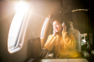 Elegant woman enjoying music with headphones while relaxing on a luxurious private jet.