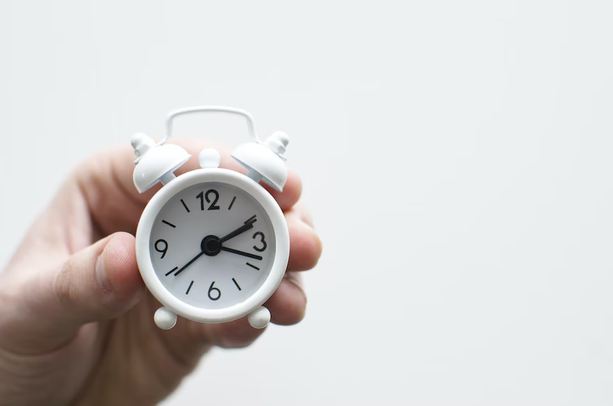 Close-up of a white clock displaying the time with clear black numbers and hands.