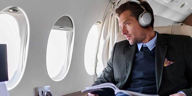 Man listening to music and gazing out of a private jet window.