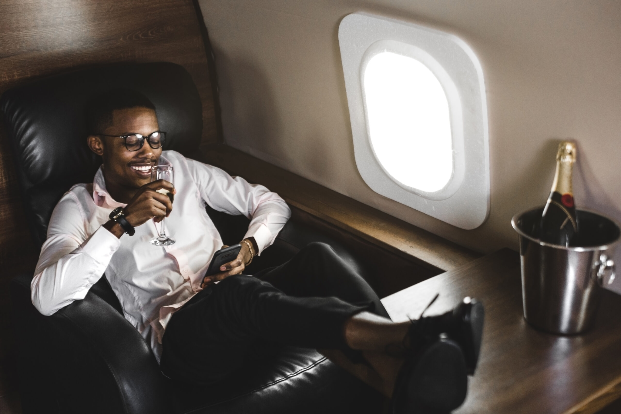 Man savoring a glass of wine while relaxing in a luxurious private jet cabin.