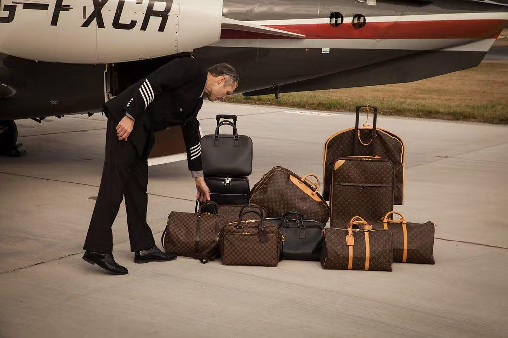 A man unloading passengers' luggage from a private jet.