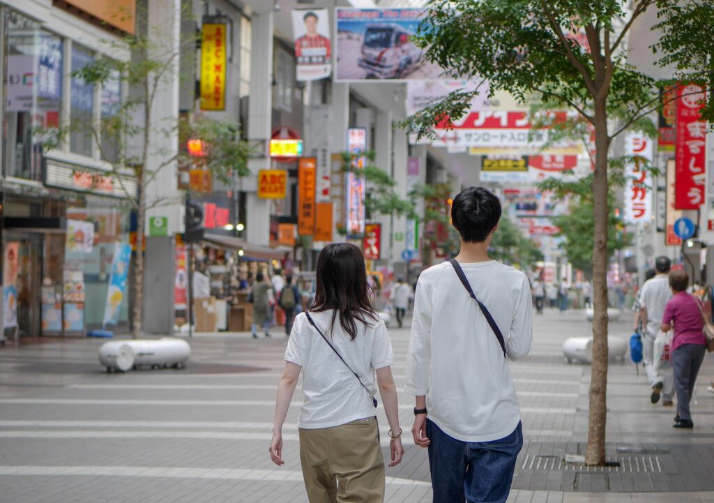 Two Japanese individuals strolling down a bustling street.