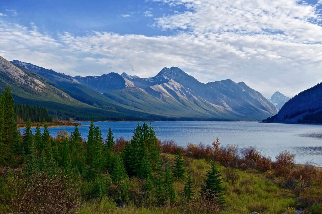 A serene river flowing through a picturesque valley, framed by majestic mountains in the background.