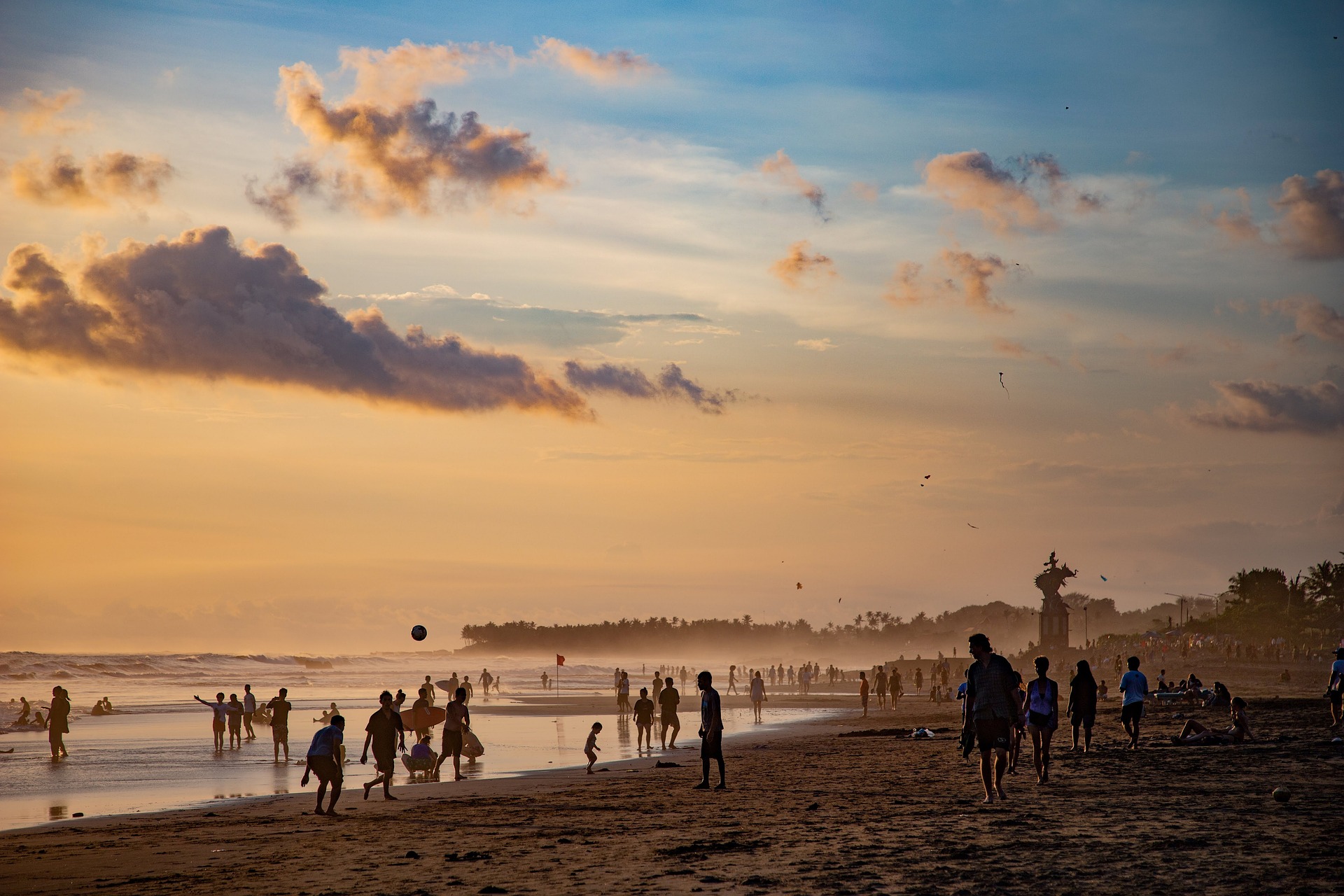 A vibrant beach scene filled with people enjoying the sun, swimming, and relaxing on the sandy shore.