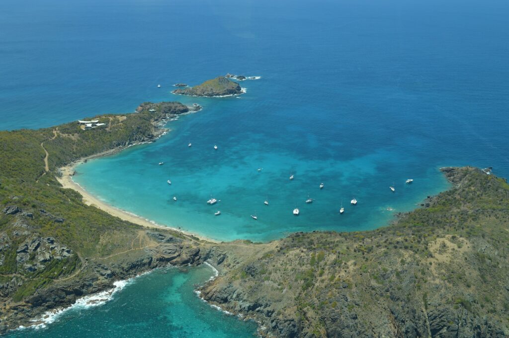 A scenic beach filled with a variety of colorful boats gently floating on the crystal-clear water.