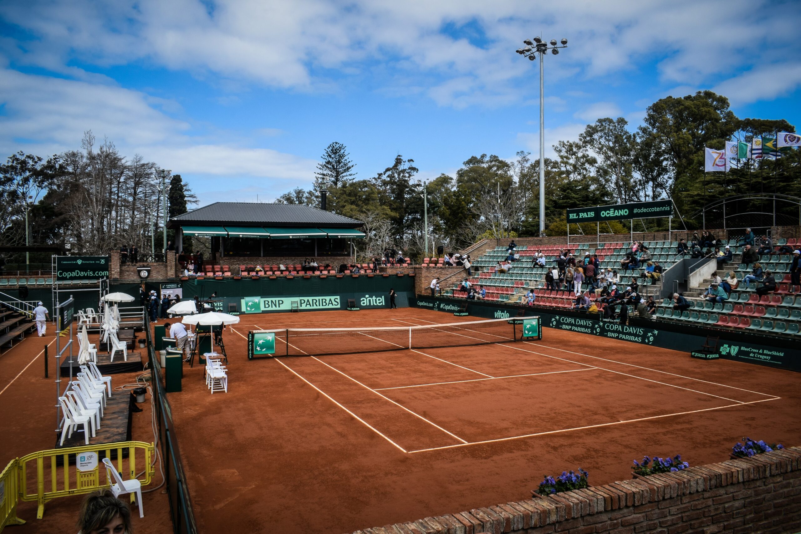 A well-maintained tennis court with adjacent bleachers for spectators.