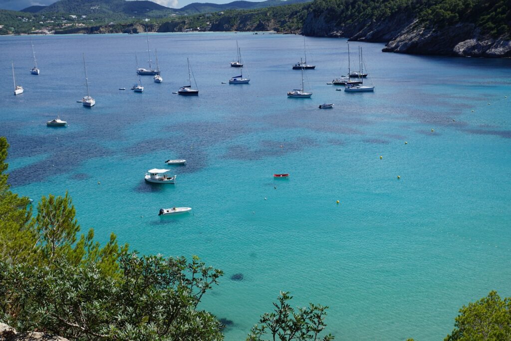 A picturesque beach dotted with numerous yachts.