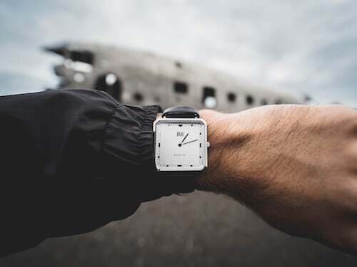 A stylish man checking his luxury watch while preparing to board a private jet.