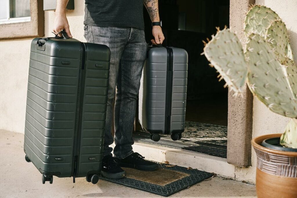 Man walking out of his house with a suitcase, heading to the airport for his flight.