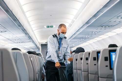 A flight attendant verifying passenger tickets during boarding on an airplane.