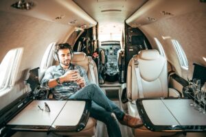 A man relaxing in a luxurious private jet, enjoying music with headphones.