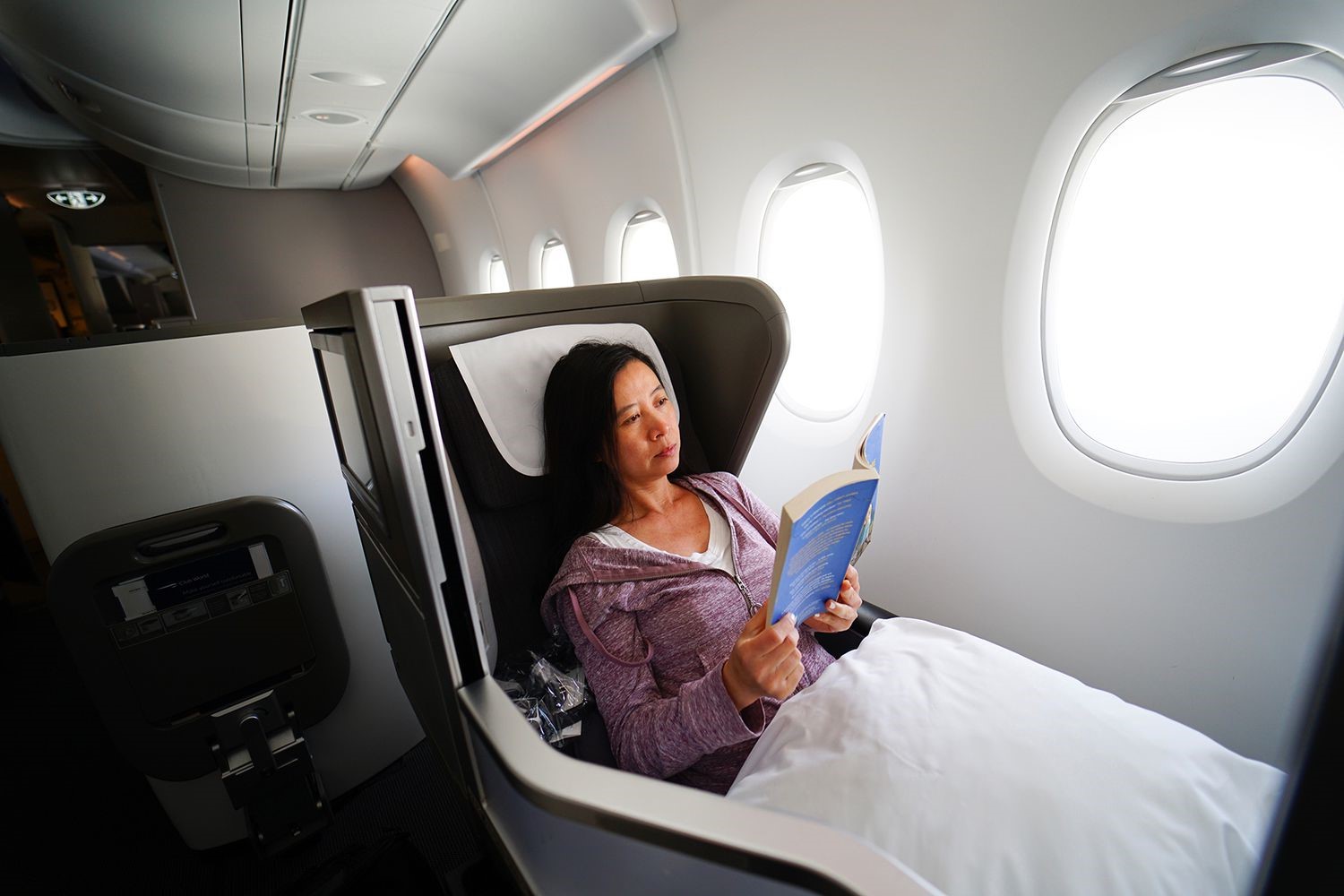 A woman relaxing in a luxurious private jet, engrossed in reading a book.