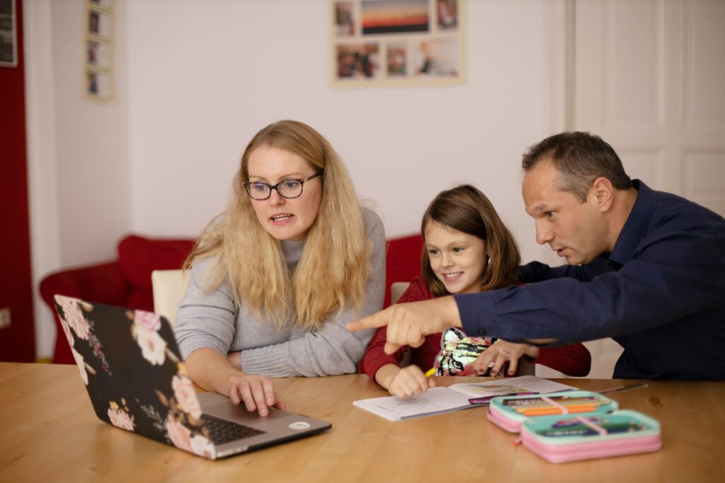 A happy family gathered around a table, planning their upcoming holiday trip with maps, a laptop, and travel brochures.