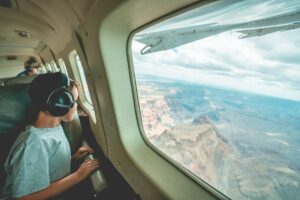 A young boy gazing out the window of a luxurious private jet, captivated by the scenic view outside.